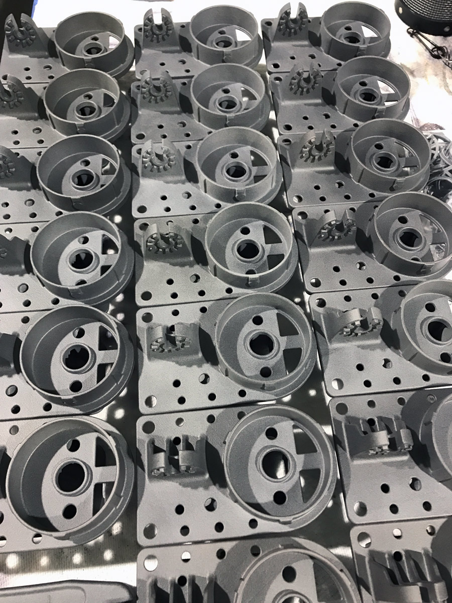 Rows of identical gray plastic mechanical parts with multiple round and rectangular holes, arranged neatly on a flat surface, showcase Ohio’s Manufacturing Strength and the precision supported by Aerosport Additive in today’s industrial landscape.