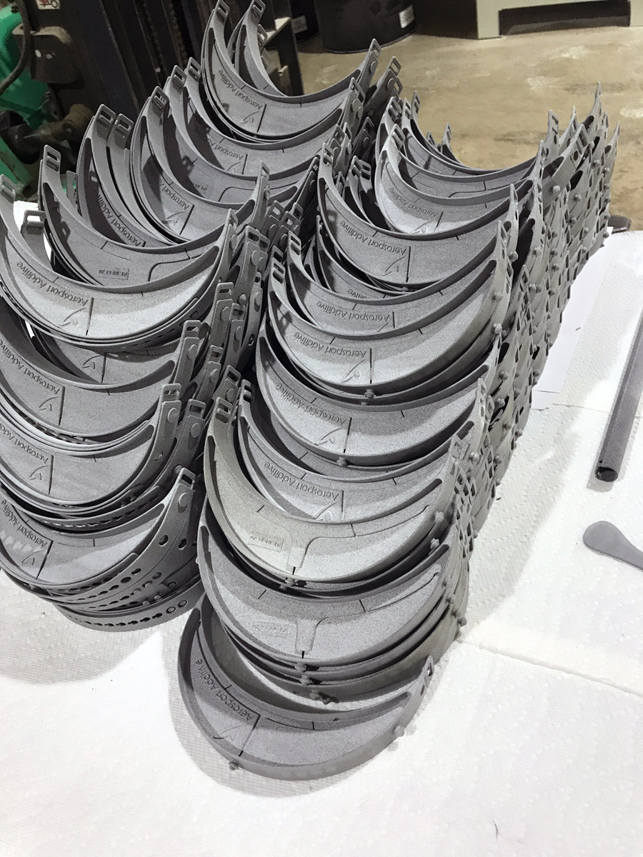 A stack of gray, curved 3D-printed face shield frames arranged neatly on a white surface, showcasing Ohio’s Manufacturing Strength in a workshop or manufacturing environment.